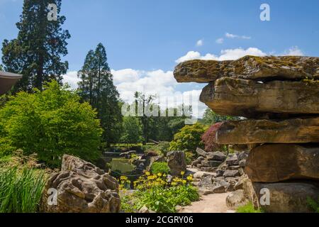 Schöne malerische Aussicht auf einen großen Stein Felsbrocken überhängend vor einem natürlichen Steingarten und leuchtend blauen Himmel Hintergrund in Peak District, Derbyshire Stockfoto