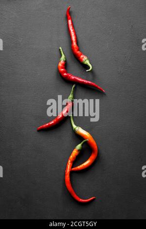 Hot Chili Peppers auf schwarzem Hintergrund, Draufsicht, Kopierbereich. Stockfoto