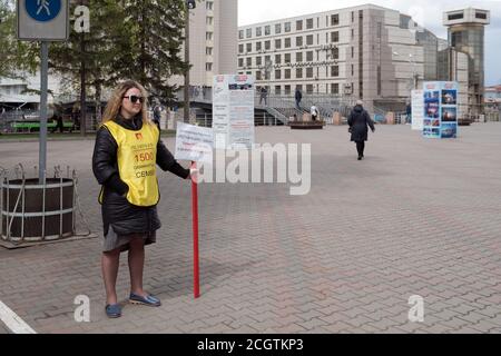 Ein Streikposten. Frauenaktivistin mit der Aufschrift auf der Kleidung: 1500 getäuschte Familien - steht vor dem Hintergrund von Stadtgebäuden. Stockfoto