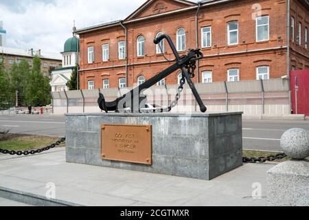 Das Denkmal ist ein Anker, der dem 100. Jahrestag der Schifffahrt auf der Jenissei gewidmet ist, vor dem Hintergrund des Gebäudes des Ministeriums für Int. Stockfoto