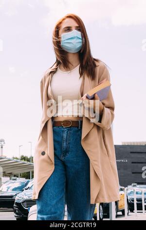 Junge Frau mit Gepäck kommt am Bahnhof vorbei Kabine Stockfoto