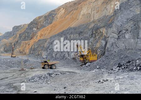 Muldenkipper Caterpillar beladen mit Nephelinerz zieht vom Bagger weg. Stockfoto