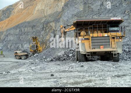 Bagger gießen Nephelinerz in Muldenkipper von Caterpillar in einer Karriere. Stockfoto