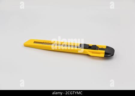 Gelbes Bürokunststoff-Papiermesser für geschnittenes Papier und andere, Nahaufnahme auf weißem Hintergrund Stockfoto