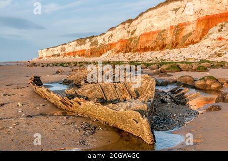 Abendsonne auf dem Wrack des Dampftrawlers Sheraton unter den rot-weiß gestreiften Klippen von Hunstanton bei Ebbe. Stockfoto