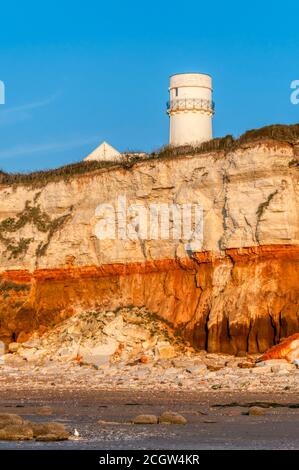 Abendsonne auf den berühmten gestreiften Klippen und der Leuchtturm auf der Klippe in Hunstanton, Norfolk. Stockfoto