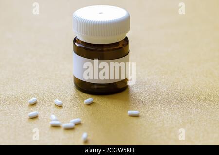 Weiße Pillen und braune Glasflasche mit Kopierplatz auf gelbem Hintergrund, gesundes und medizinisches Konzept. Stockfoto