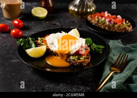 Gesundes Sandwich mit offenem pochiertem Ei auf schwarzem Hintergrund. Nahaufnahme. Gesunde Ernährung Konzept Stockfoto