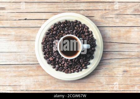 Heißer Espresso in weißer Tasse und geröstete Kaffeebohnen auf einem Holztisch, Draufsicht. Stockfoto