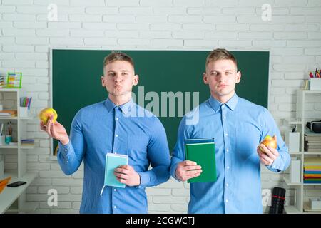 Brothers Student Lernen in der Universität. Zwei attraktive positive Lächeln junge Studenten stehen und halten Buch. Glückliche männliche Studenten mit Büchern Stockfoto