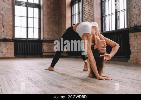 Junge Frau machen Komplex von Stretching Yoga Asanas im Loft-Stil Klasse. Camatkarasana, Wild Thing, Flip-the-Dog Pose. Stockfoto