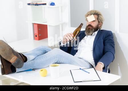 Gelangweilter betrunkener Geschäftsmann im Büro am Ende des Arbeitstages. Geschäftsmann trinkt von Stress. Stockfoto