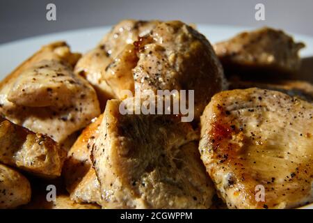 Stücke gebratenes Hähnchenfilet mit schwarzem Pfeffer bestreut Stockfoto