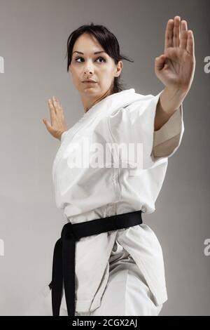 Mädchen Ausübung Karate, posiert vor grauem Hintergrund Stockfoto