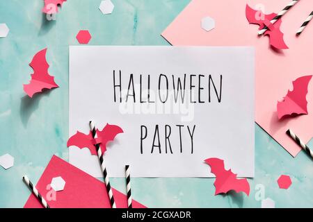 Text Halloween Party auf geschichteten Papier Hintergrund in mintgrün und pastellrosa. Flach legen, trendige Halloween-Dekorationen - Hexagon Konfetti, Papiergetränk Stockfoto