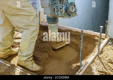 Arbeiter verwendet Verdichter zu Vibrations-Elektrowerkzeug am Boden bei Baustelle Bau neuer Gehweg Stockfoto