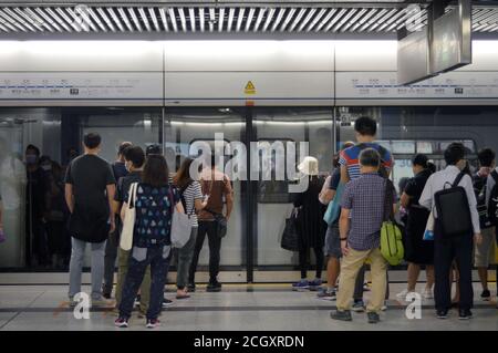 Passagiere, die Schlange stehen, um in Hongkong an Bord eines U-Bahn-Zuges zu gehen Stockfoto