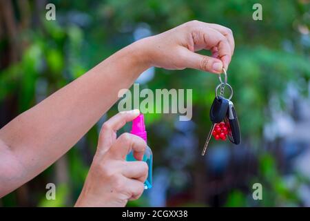 Asiatische Frauen spry Alkohol zu reinigen Autoschlüssel, Konzept für Coronavirus, Covit-19 Prävention und Desinfektion. Stockfoto