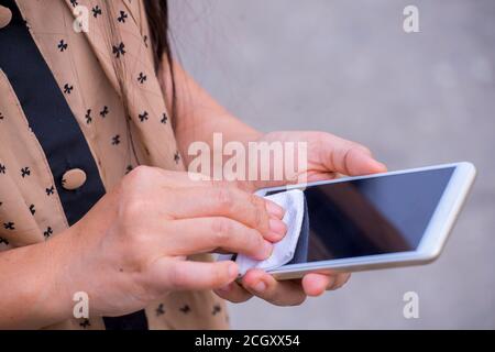 Junge asiatische Frau Reinigung Handy-Bildschirm mit weichem Papier Serviette. Coronavirus, Covit-19 Prävention und Desinfektion. Stockfoto