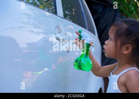 Asiatische Kinder Spry Seife zu reinigen Auto Tür Griff. Stockfoto