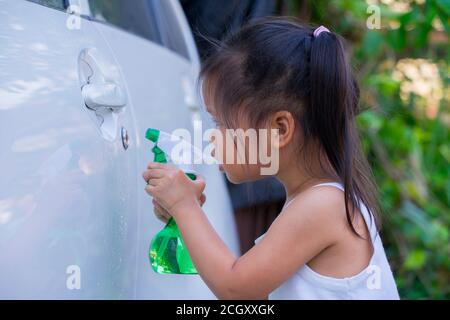 Asiatische Kinder Spry Seife zu reinigen Auto Tür Griff. Stockfoto