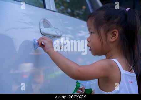 Asiatische Kinder Spry Seife zu reinigen Auto Tür Griff. Stockfoto