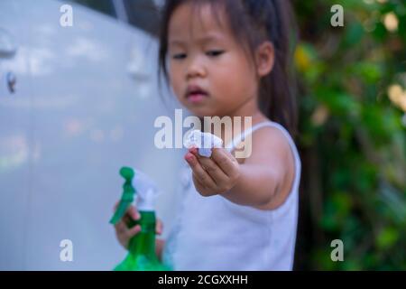 Asiatische Kinder Spry Seife zu reinigen Auto Tür Griff. Stockfoto