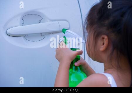 Asiatische Kinder Spry Seife zu reinigen Auto Tür Griff. Stockfoto