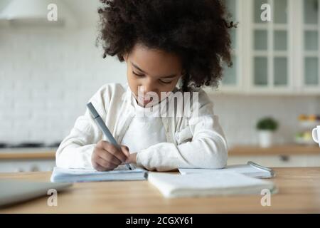 afroamerikanische Kind Mädchen Handschrift Schule Aufgaben allein zu Hause. Stockfoto