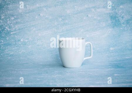 Weiße Tasse für Kaffee auf einem blauen Hintergrund. Seitenansicht, isolieren Stockfoto