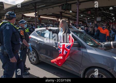 Melbourne, Australien. September 2020. Viktorianische Polizisten sprechen mit einem Protestanten, der auf den Queen Victoria Markets eine rote Flagge weckend, während eines Popup-Anti-Maske- und Anti-Lockdown-Protests auf dem Markt in Melbourne Australia. Kredit: Michael Currie/Alamy Live Nachrichten Stockfoto