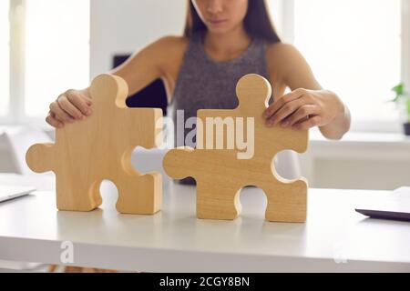 Business Frau stehen und versuchen, das ganze Bild aus zu machen Holzdetails Puzzle allein im Büro