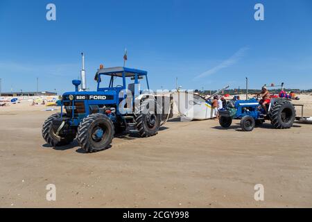 Costa da Caparica, Portugal - 10. September 2020: Eine Kunst der Fischer Schleppnetzfischfang vom touristischen Strand mit einem Traktor. Urlauber beobachten und hellen Stockfoto