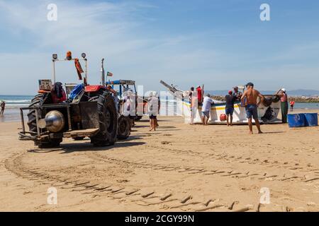 Costa da Caparica, Portugal - 10. September 2020: Eine Kunst der Fischer Schleppnetzfischfang vom touristischen Strand mit einem Traktor. Urlauber beobachten und hellen Stockfoto