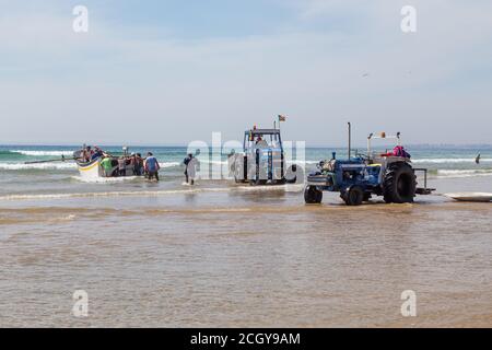 Costa da Caparica, Portugal - 10. September 2020: Eine Kunst der Fischer Schleppnetzfischfang vom touristischen Strand mit einem Traktor. Urlauber beobachten und hellen Stockfoto