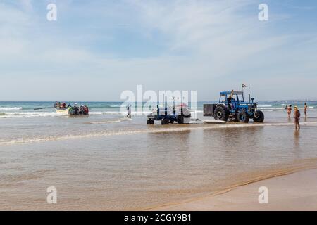 Costa da Caparica, Portugal - 10. September 2020: Eine Kunst der Fischer Schleppnetzfischfang vom touristischen Strand mit einem Traktor. Urlauber beobachten und hellen Stockfoto