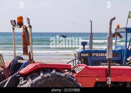 Costa da Caparica, Portugal - 10. September 2020: Eine Kunst der Fischer Schleppnetzfischfang vom touristischen Strand mit einem Traktor. Urlauber beobachten und hellen Stockfoto