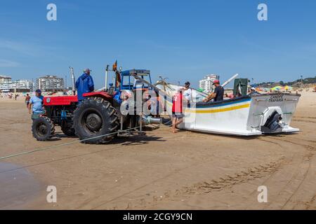 Costa da Caparica, Portugal - 10. September 2020: Eine Kunst der Fischer Schleppnetzfischfang vom touristischen Strand mit einem Traktor. Urlauber beobachten und hellen Stockfoto