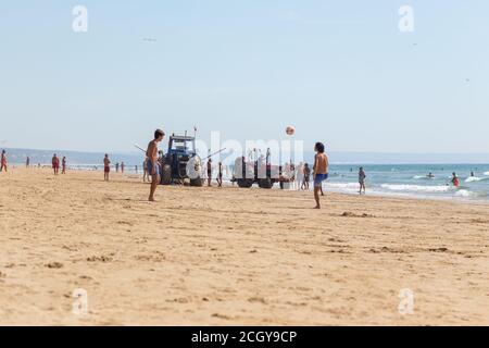 Costa da Caparica, Portugal - 10. September 2020: Eine Kunst der Fischer Schleppnetzfischfang vom touristischen Strand mit einem Traktor. Urlauber beobachten und hellen Stockfoto