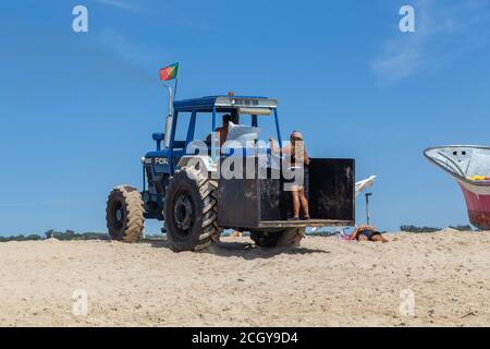 Costa da Caparica, Portugal - 10. September 2020: Eine Kunst der Fischer Schleppnetzfischfang vom touristischen Strand mit einem Traktor. Urlauber beobachten und hellen Stockfoto