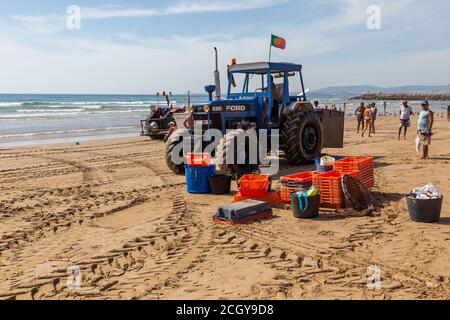 Costa da Caparica, Portugal - 10. September 2020: Eine Kunst der Fischer Schleppnetzfischfang vom touristischen Strand mit einem Traktor. Urlauber beobachten und hellen Stockfoto