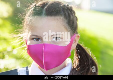 Nahaufnahme des Gesichts eines 10-jährigen Mädchens mit ihren Haaren in Zöpfen und einer rosa Gesichtsmaske. Stockfoto