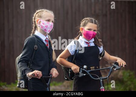 Zwei 10-jährige Schülerinnen in Schuluniform und tragen Gesichtsmasken Stockfoto