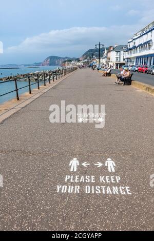 Anweisungen, bitte halten Sie Ihren Abstand, gemalt auf dem Bürgersteig an der Strandpromenade in Sidmouth, einer Küstenstadt in Devon an der Südküste Stockfoto