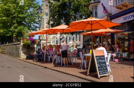 Essen im Freien an einem sonnigen Tag im Stadtzentrum von Sidmouth, einer Küstenstadt in Devon, auf dem Weltkulturerbe der Jurassic Coast Stockfoto