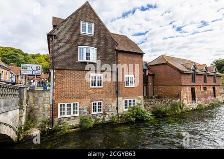 Der Fluss Itchen fließt durch historische Gebäude am Flussufer an den Wehren in Winchester, Hampshire, Südengland Stockfoto