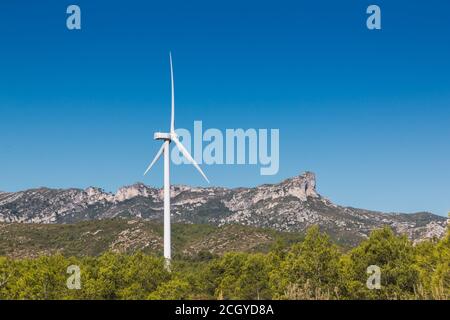 Stock Foto von einer Windmühle auf einem bewaldeten Berg und blauen Himmel. Es gehört zu einem Windpark Stockfoto