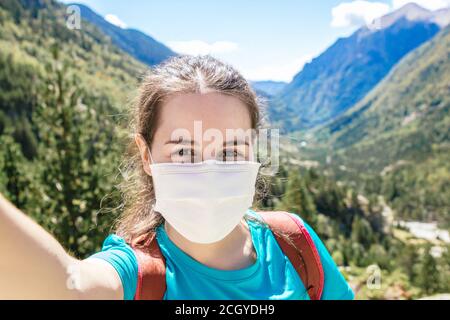 Stock Foto einer Frau mit Gesichtsmaske Selfie Foto In den Bergen und eine schöne Landschaft im Hintergrund Stockfoto