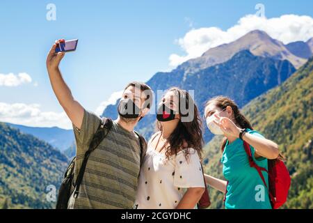 Stock Foto einer Gruppe von Freunden tragen Gesichtsmasken Und ein Selfie beim Wandern in den Bergen und Genießen Sie die Landschaft Stockfoto