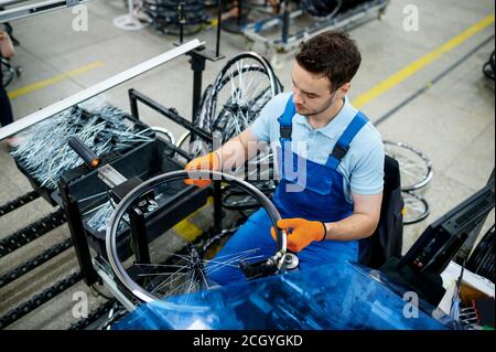 Arbeiter mit Werkzeugmaschine installiert Fahrradspeichen Stockfoto